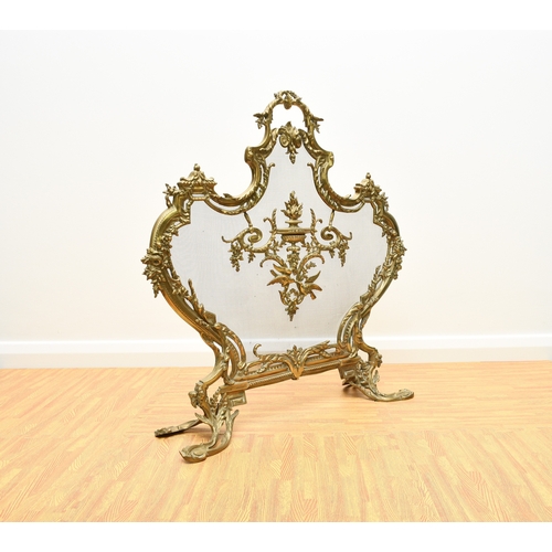 159 - A rococo revival cast brass fire screen Of shield form and cast in relief with scrolling foliage and... 