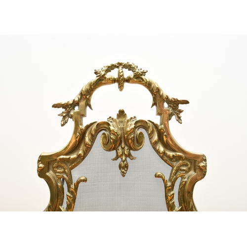 159 - A rococo revival cast brass fire screen Of shield form and cast in relief with scrolling foliage and... 
