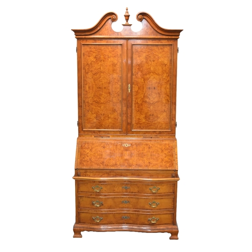 203 - A good reproduction walnut bureau cabinet The swan-neck pediment above twin panelled doors with inte... 