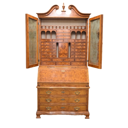 203 - A good reproduction walnut bureau cabinet The swan-neck pediment above twin panelled doors with inte... 
