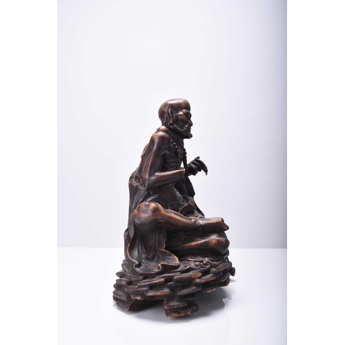 114 - A Chinese carved wood figure of a seated Luohan, Qing Dynasty The emaciated figure sitting on a rock... 