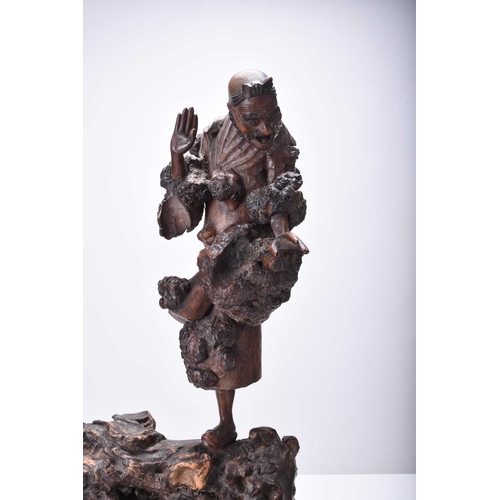 118 - A Chinese carved root wood figure of Luohan, Qing Dynasty Modelled standing on a large knotty root. ... 