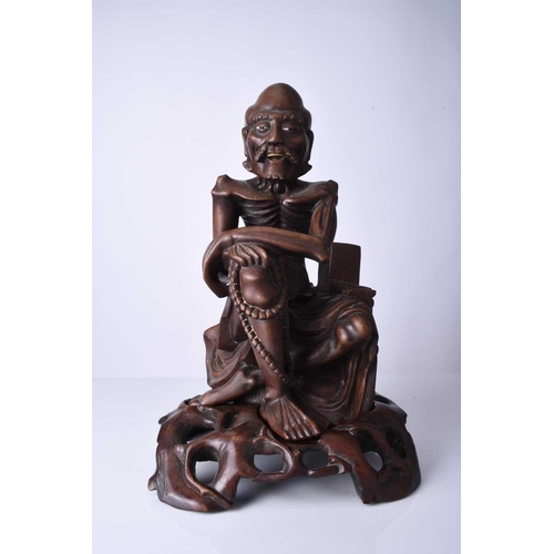 122 - A Chinese carved hardwood figure of a luohan, 19th century The emaciated figure modelled seated and ... 