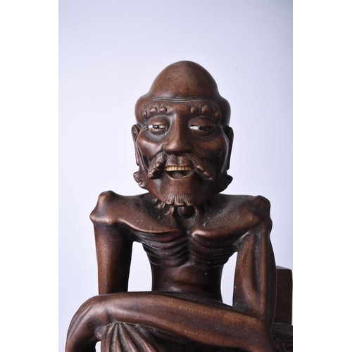 122 - A Chinese carved hardwood figure of a luohan, 19th century The emaciated figure modelled seated and ... 