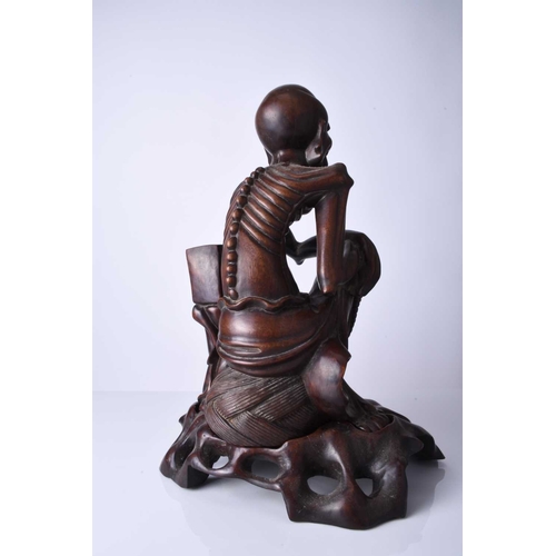 122 - A Chinese carved hardwood figure of a luohan, 19th century The emaciated figure modelled seated and ... 