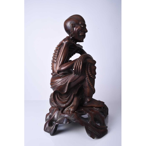 122 - A Chinese carved hardwood figure of a luohan, 19th century The emaciated figure modelled seated and ... 