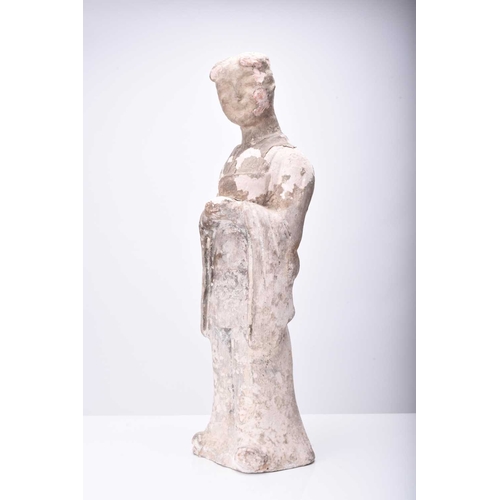 25 - A large Chinese buff pottery figure of a maiden, Sui/Tang Dynasty Modelled standing and wearing long... 