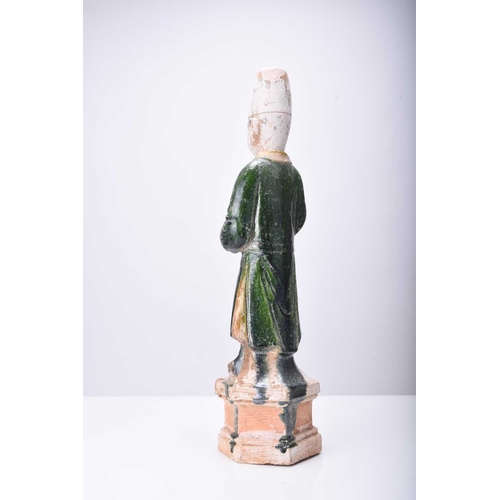 26 - A Chinese Sancai green-glazed standing figure, Tang Dynasty Modelled as an attendant, set on a hexag... 