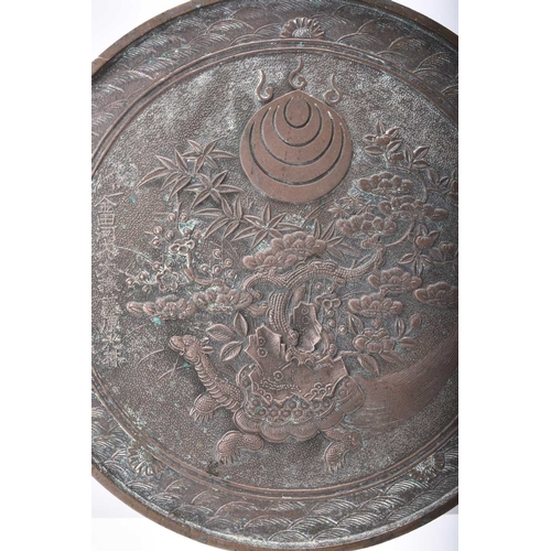 271 - A Japanese bronze mirror, Meiji/Taisho era Of circular form with plain handle, cast in low relief wi... 