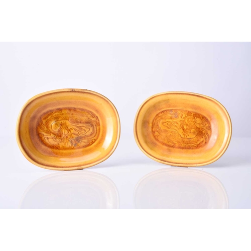 37 - A pair of Chinese Sancai amber glazed dragon dishes Possibly Kangxi, of oval form, each incised with... 