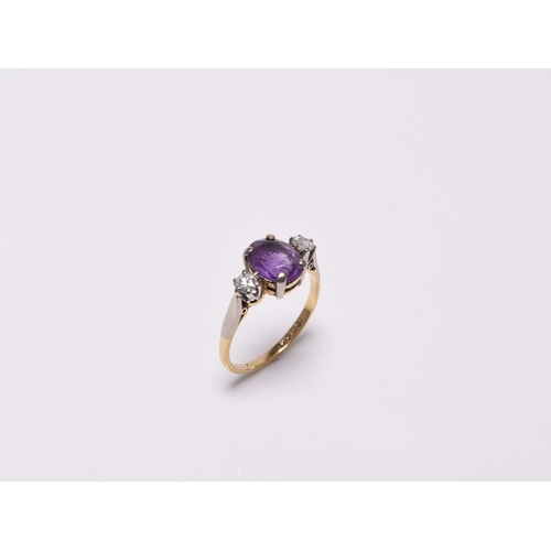 366 - A three stone amethyst and diamond ring, designed as a central oval mixed cut amethyst claw set in w... 