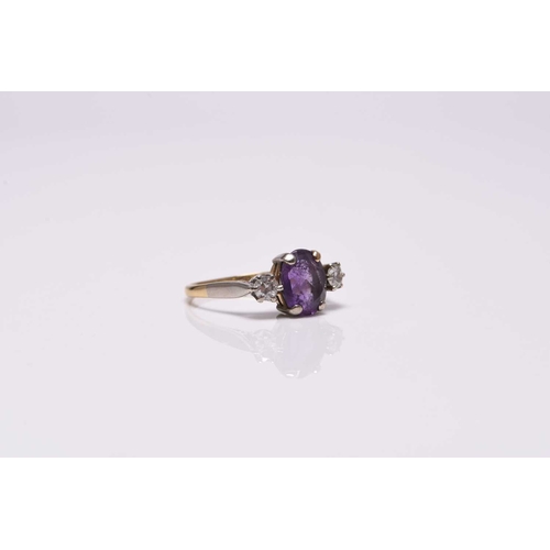 366 - A three stone amethyst and diamond ring, designed as a central oval mixed cut amethyst claw set in w... 