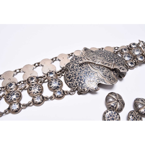 39 - A Russian silver niello work belt, the scrolling panel clasp secured with novelty Kindjal, together ... 