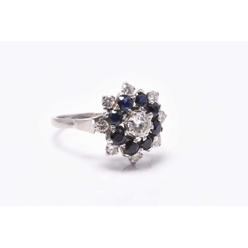 26 - A sapphire and diamond circular cluster ring, designed as a central brilliant cut diamond claw set w... 