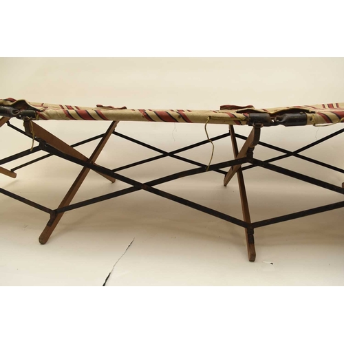 113 - A First World War British Army officer's folding campaign bed, with original red and white striped f... 