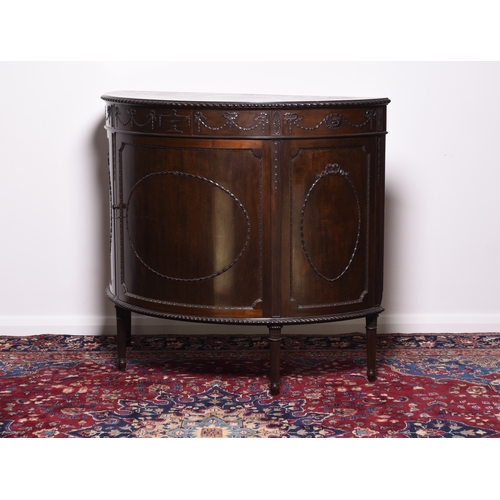 218 - A Regency style mahogany demi-lune cabinet The moulded top above a frieze carved with swags and pate... 