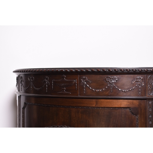 218 - A Regency style mahogany demi-lune cabinet The moulded top above a frieze carved with swags and pate... 