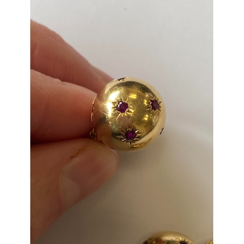 50 - A pair of ruby set orb rings, each designed as a yellow metal polished orb set with eight round face... 