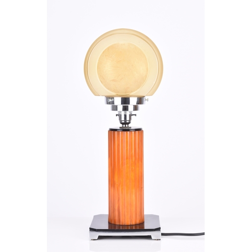 236 - An Art Deco table lamp The stepped chrome lamp head on a reeded 'amber' stem, set on a black composi... 