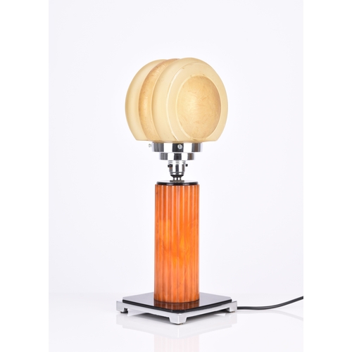 236 - An Art Deco table lamp The stepped chrome lamp head on a reeded 'amber' stem, set on a black composi... 