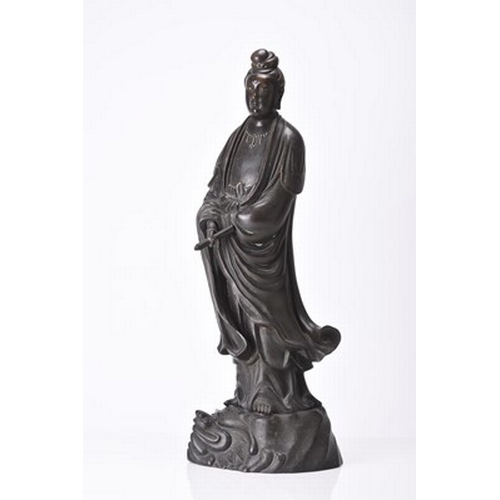 101 - A large Chinese silver-inlaid bronze figure of Guanyin, Qing Dynasty Modelled standing on top of a d... 