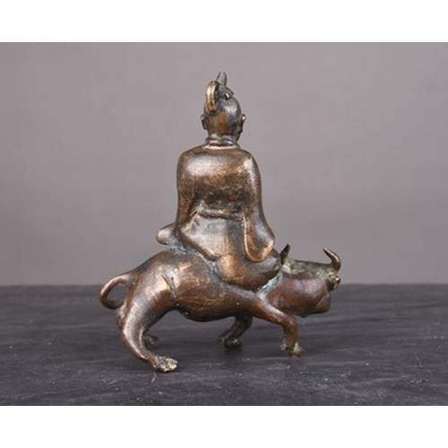 108 - A Chinese bronze figural scroll weight, Qing Dynasty Modelled as a lohan riding a buffalo. 8cm high