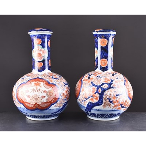 201 - A pair of Japanese Imari vases and covers, Meiji era Of bottle form and decorated with shaped panels... 