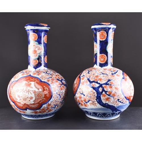 201 - A pair of Japanese Imari vases and covers, Meiji era Of bottle form and decorated with shaped panels... 