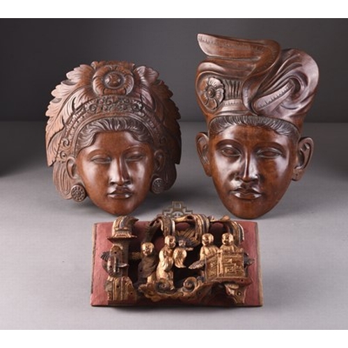 253 - A pair of Balinese carved wood wall masks Depicting a male and female with elaborate headdresses, in... 