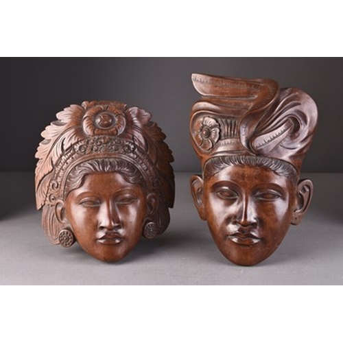 253 - A pair of Balinese carved wood wall masks Depicting a male and female with elaborate headdresses, in... 