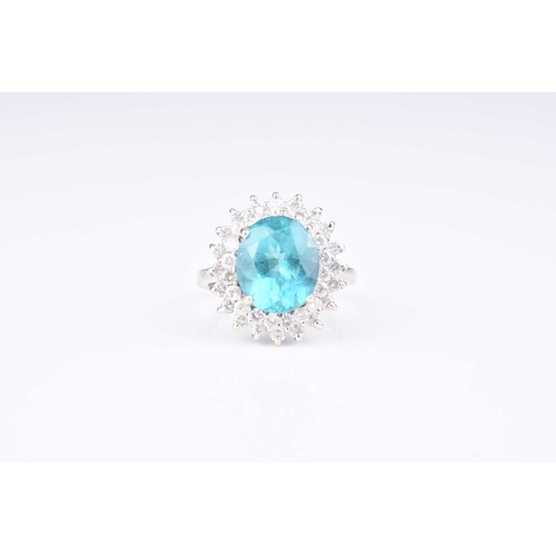 109 - A blue apatite and diamond cluster ring, designed as a central oval mixed cut blue apatite claw set ... 