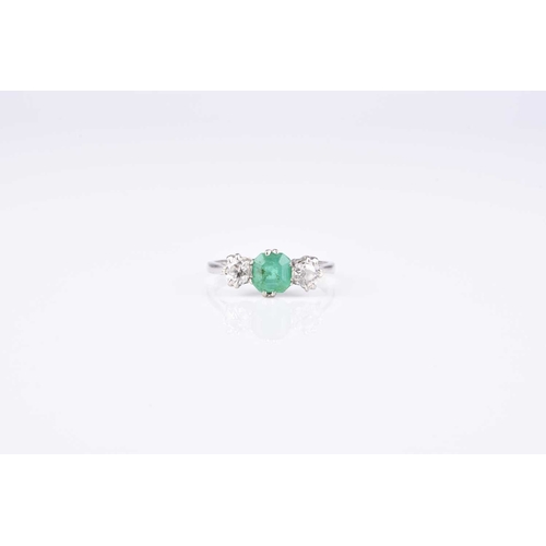 121 - A graduated three stone emerald and diamond ring, designed as a central trap cut emerald flanked to ... 