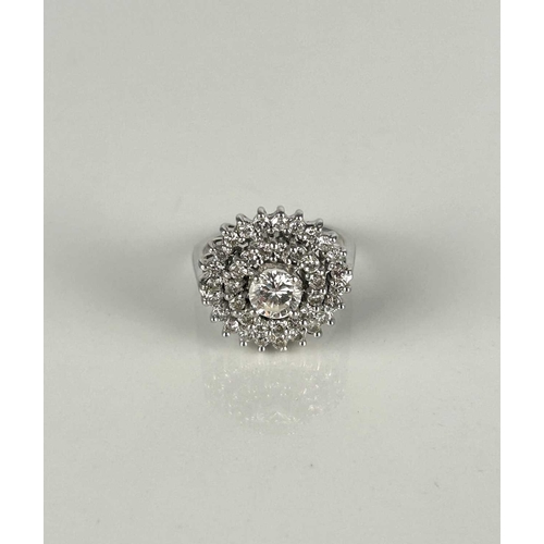 131 - A diamond cluster ring, designed as a central raised brilliant cut diamond claw set within two circu... 