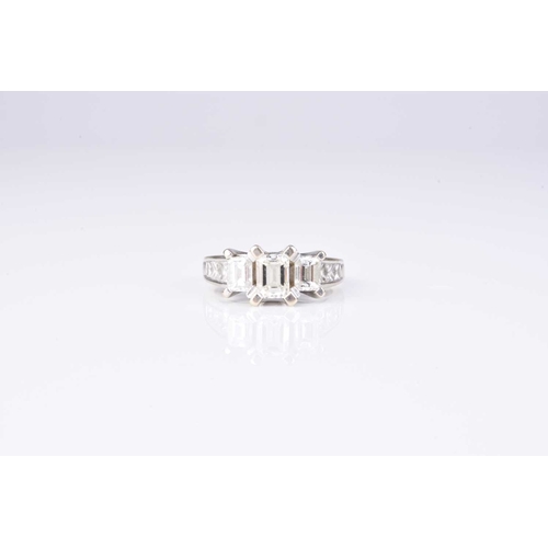 159 - A graduated emerald cut three stone diamond ring, the three emerald cut diamonds claw set in white m... 