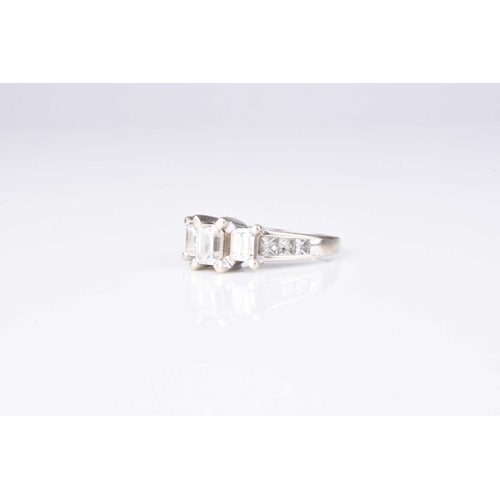 159 - A graduated emerald cut three stone diamond ring, the three emerald cut diamonds claw set in white m... 