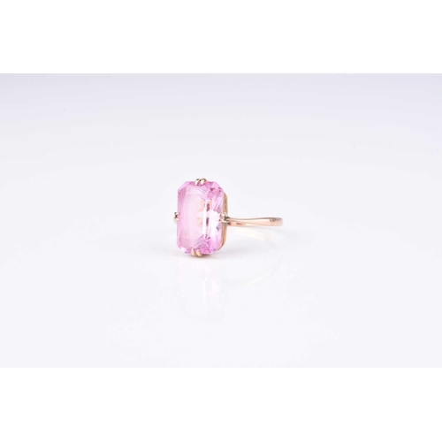 163 - A single stone synthetic pink sapphire ring, the faceted rectangular cut pink stone claw set in yell... 