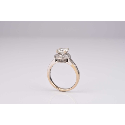 166 - A brilliant cut diamond halo ring, the central raised diamond claw set in white metal within a borde... 