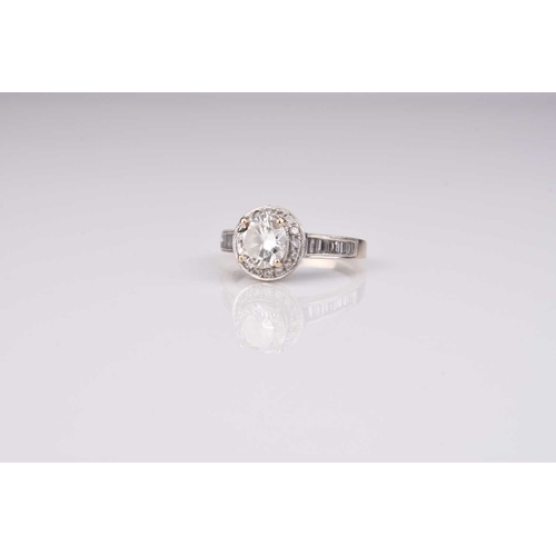 166 - A brilliant cut diamond halo ring, the central raised diamond claw set in white metal within a borde... 