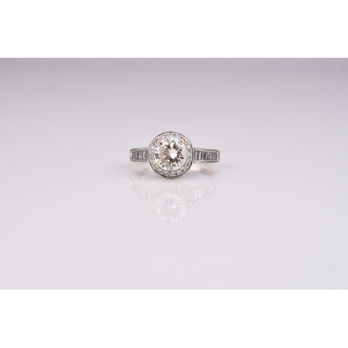 166 - A brilliant cut diamond halo ring, the central raised diamond claw set in white metal within a borde... 