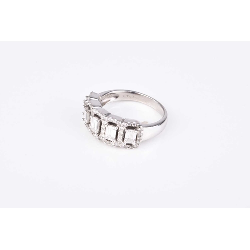 203 - A diamond dress ring, designed as five emerald cut diamonds claw set in white metal within borders o... 