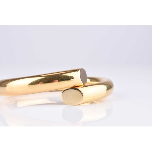 241 - A yellow metal hinged bangle, of polished form with central hinge to the base, inner width approx 60... 