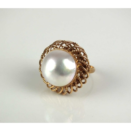 255 - A Mabe pearl ring, the large mabe pearl measures approx 15mm diameter set to stylised openwork yello... 