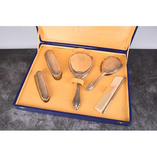 35 - A cased white metal mounted dressing table set, comprising; a hand mirror, three brushes and a comb,... 