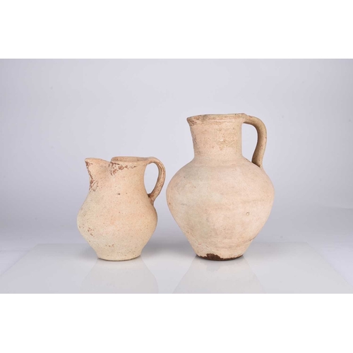 34 - Two Roman earthenware pitchers Circa 2nd century AD The buff pottery of ovoid form with pinched spou... 