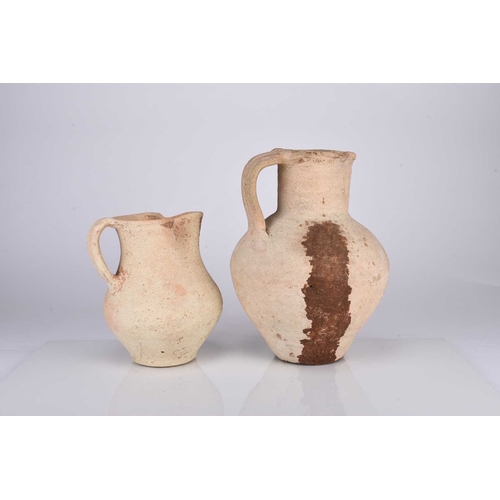 34 - Two Roman earthenware pitchers Circa 2nd century AD The buff pottery of ovoid form with pinched spou... 