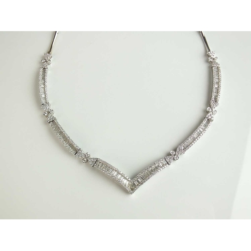 137 - An 18ct white gold diamond set necklace, designed as a central chevron panel channel set with baguet... 