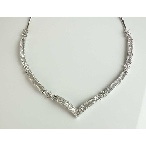 137 - An 18ct white gold diamond set necklace, designed as a central chevron panel channel set with baguet... 