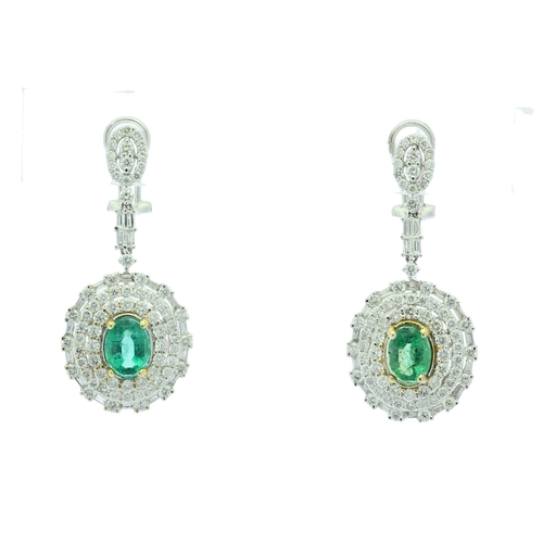 36 - Each of these drop earrings are set with one stunning emerald gemstone sitting in a double halo of f... 