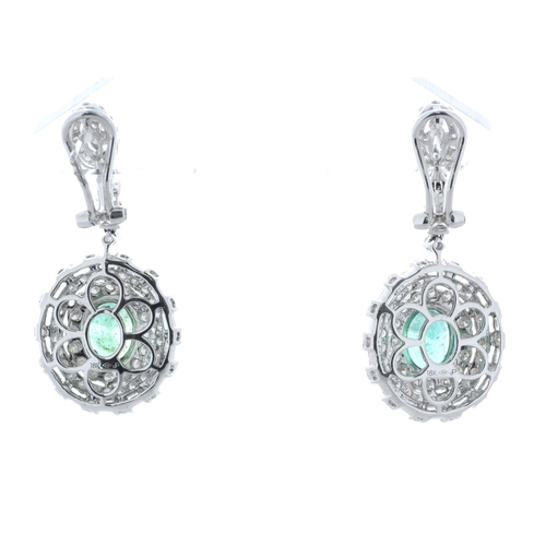 36 - Each of these drop earrings are set with one stunning emerald gemstone sitting in a double halo of f... 