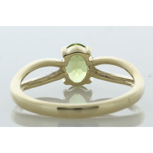 65 - An oval 7mm x 5mm peridot sits between a double band of eight round brilliant cut diamonds set in th... 